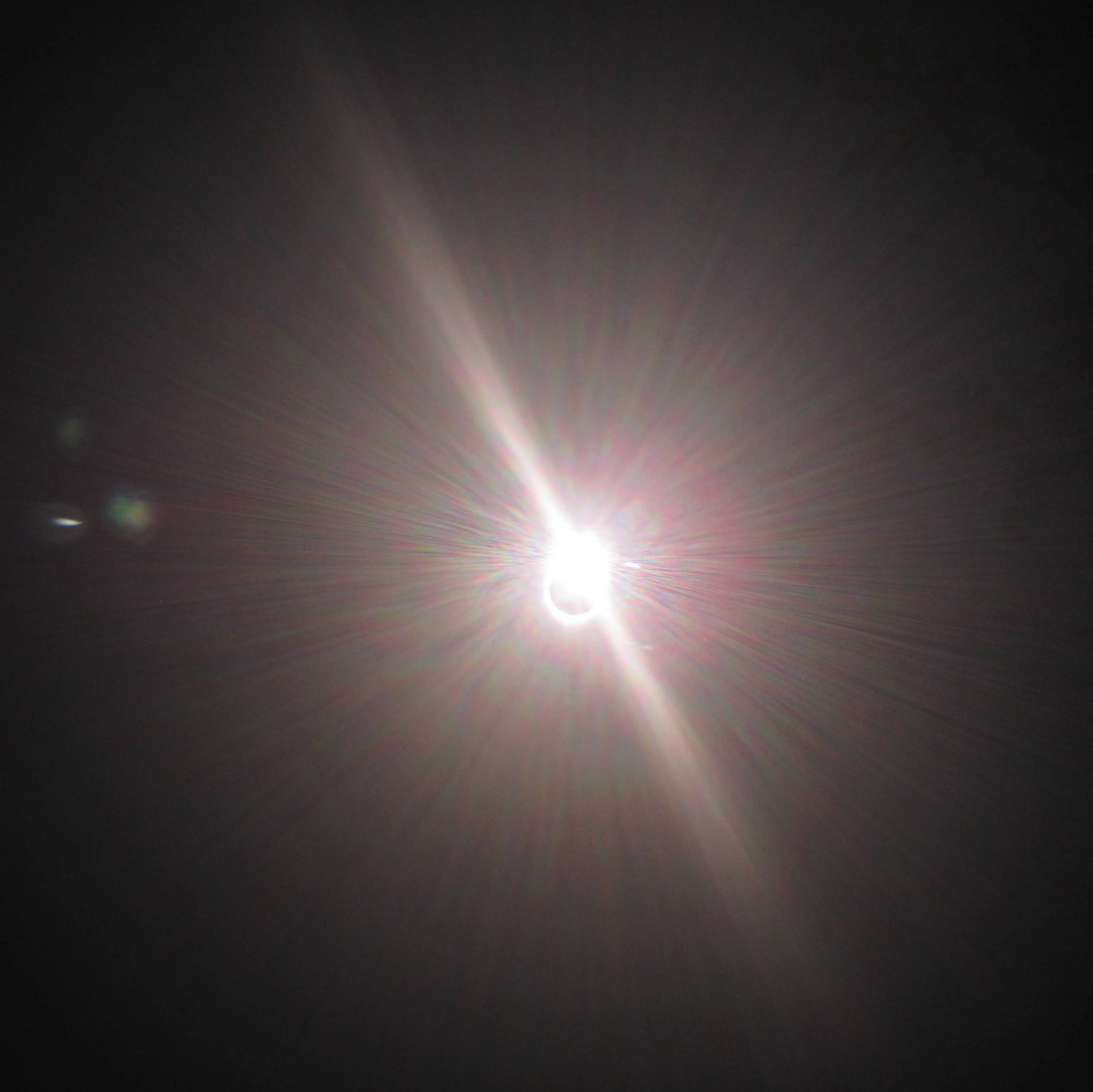A black circle with a white outline.  The top right of the outline shines brightly like the sun, obscuring half the circle.  The background of the picture is black.