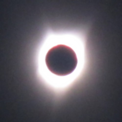 A black circle, in front of a white fuzzy blob, which is surrounded by black sky