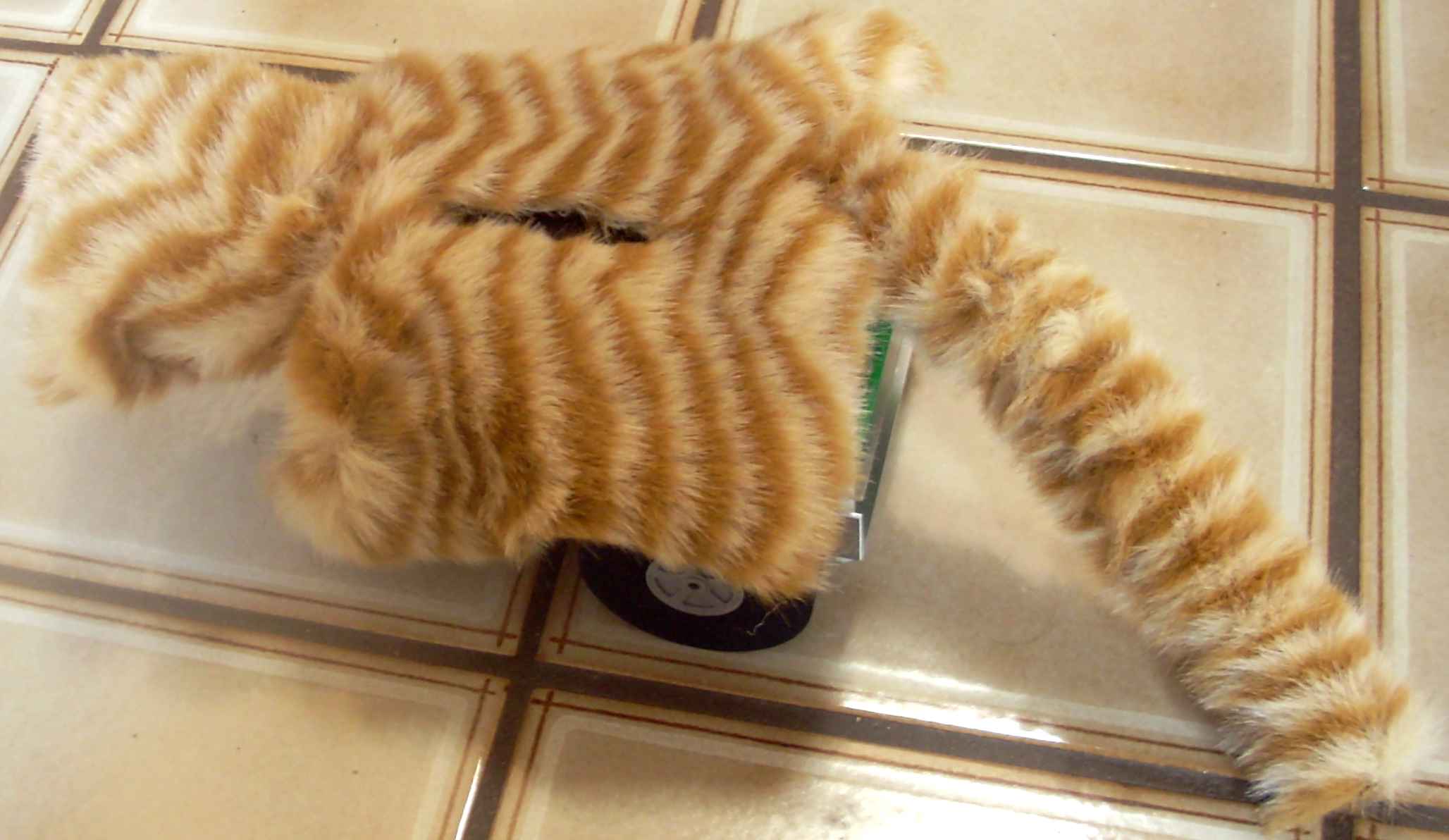 Top view, showing the top of the head and the tail.  It has orange stripey fur, and looks kind of boxy, and you can see a wheel, and there's a rectangular hole in the top (for the display).